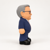 Side view of the MEGA Anthony Albanese dog toy showing its grey hair, glasses, navy suit and black shoes.